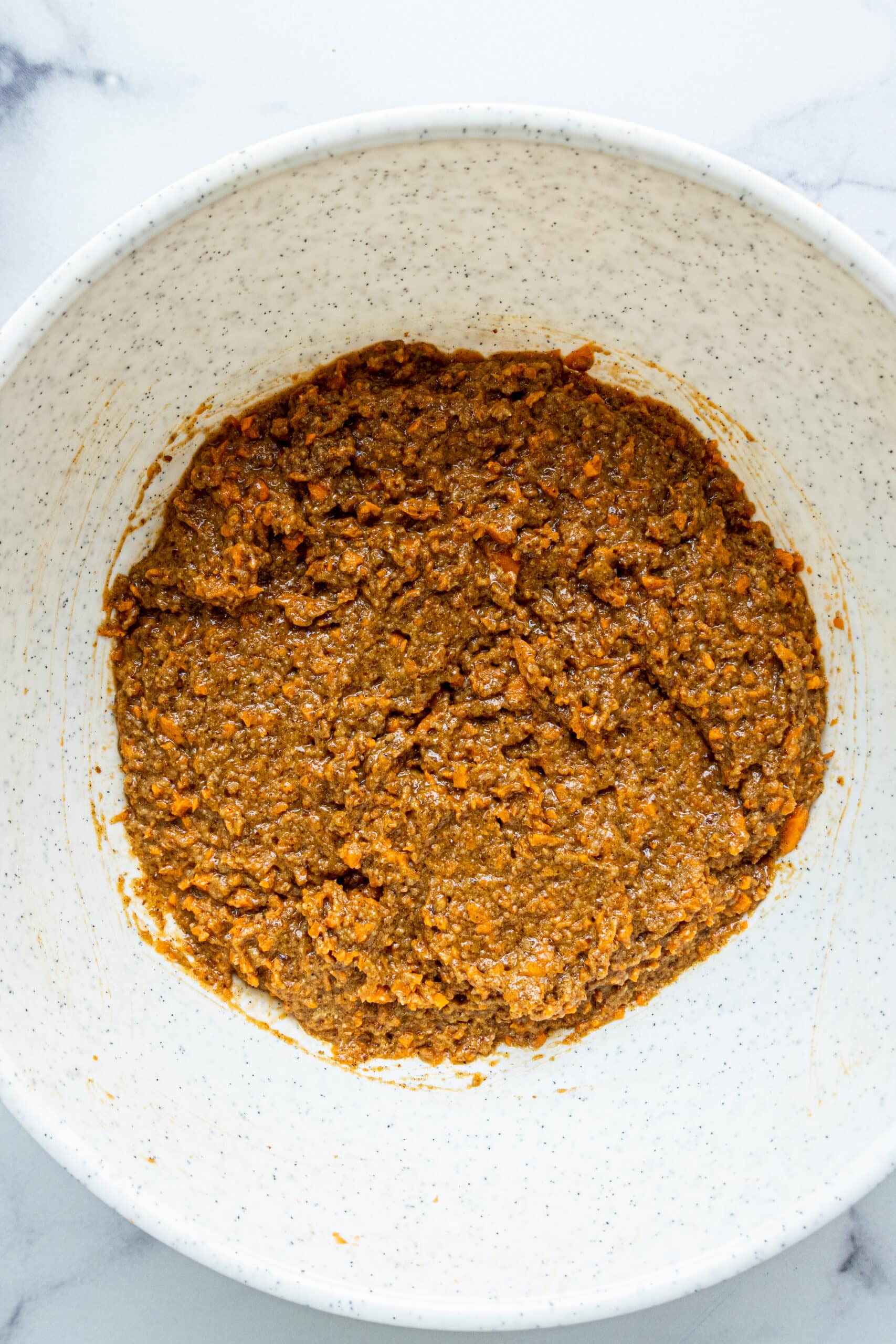 A large white bowl filled with carrot cake batter.