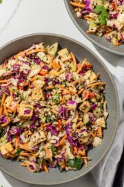 thai chopped salad in a grey bowl with a white towel next to it on the counter and a second bowl of thai chopped salad in the corner.