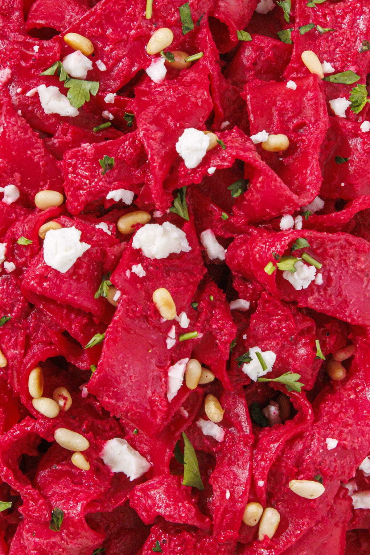 Pink pasta topped with goat cheese, pine nuts, and fresh parsley.