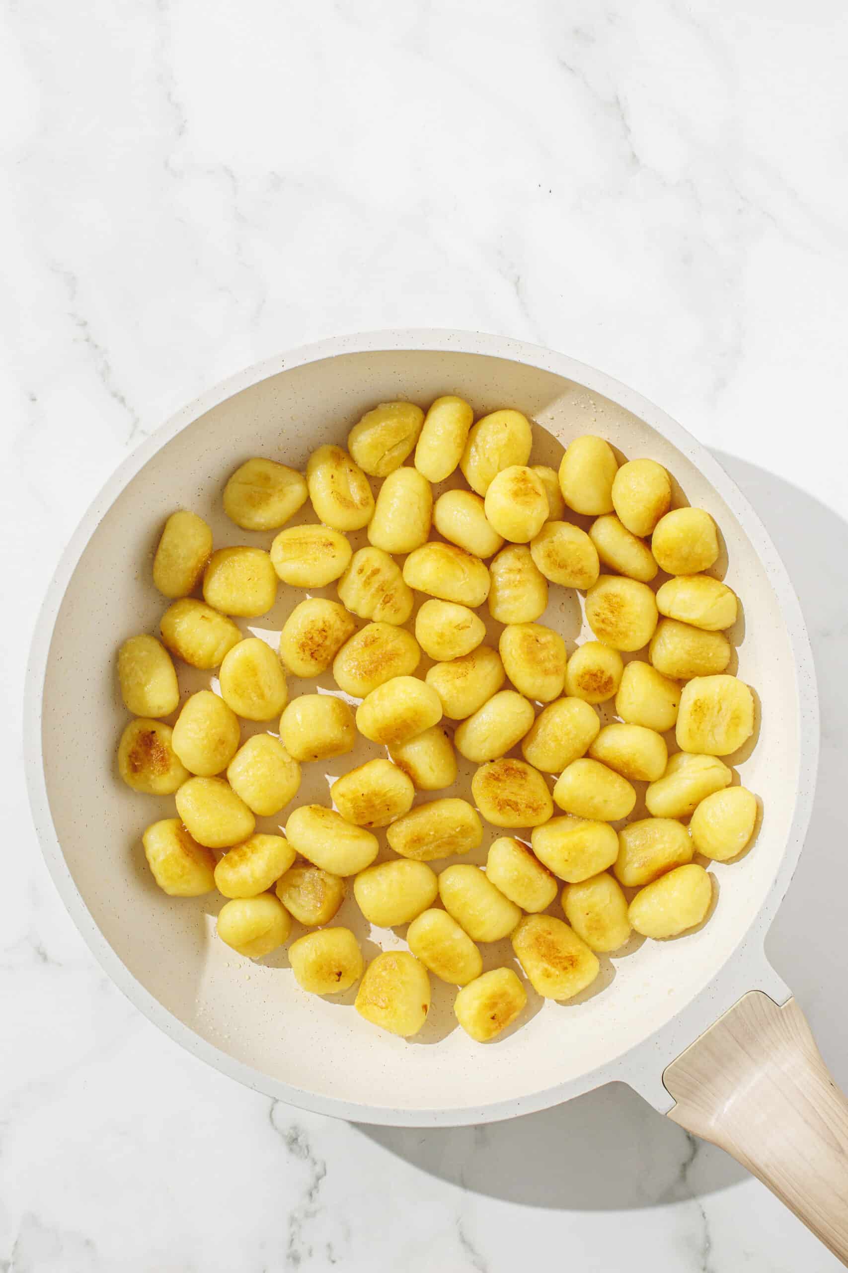 A small white pan filled with gnocchi getting ready to be sauteed.