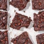 Nine brownies on a piece of parchment paper. The center brownie has a bite taken out of it.