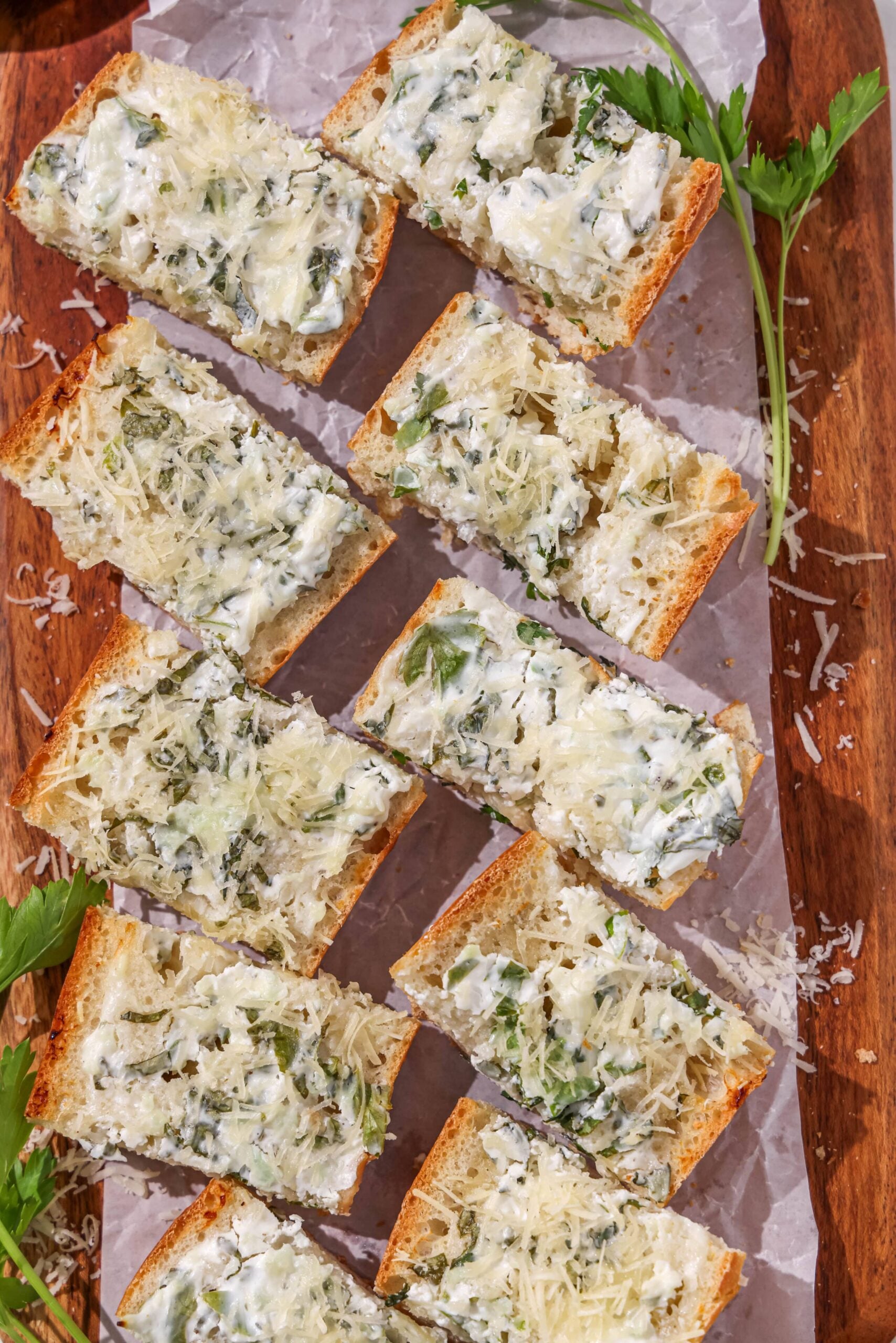 Sliced garlic bread pieces on a wooden cutting board.