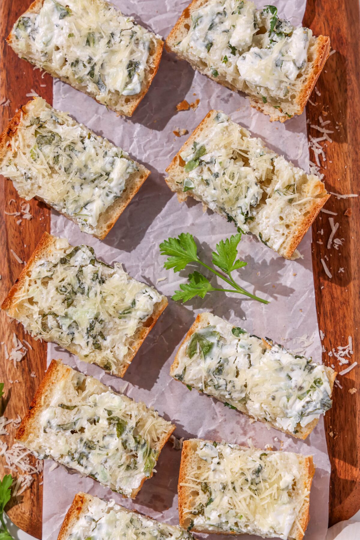 Sliced garlic bread pieces on a wooden cutting board.