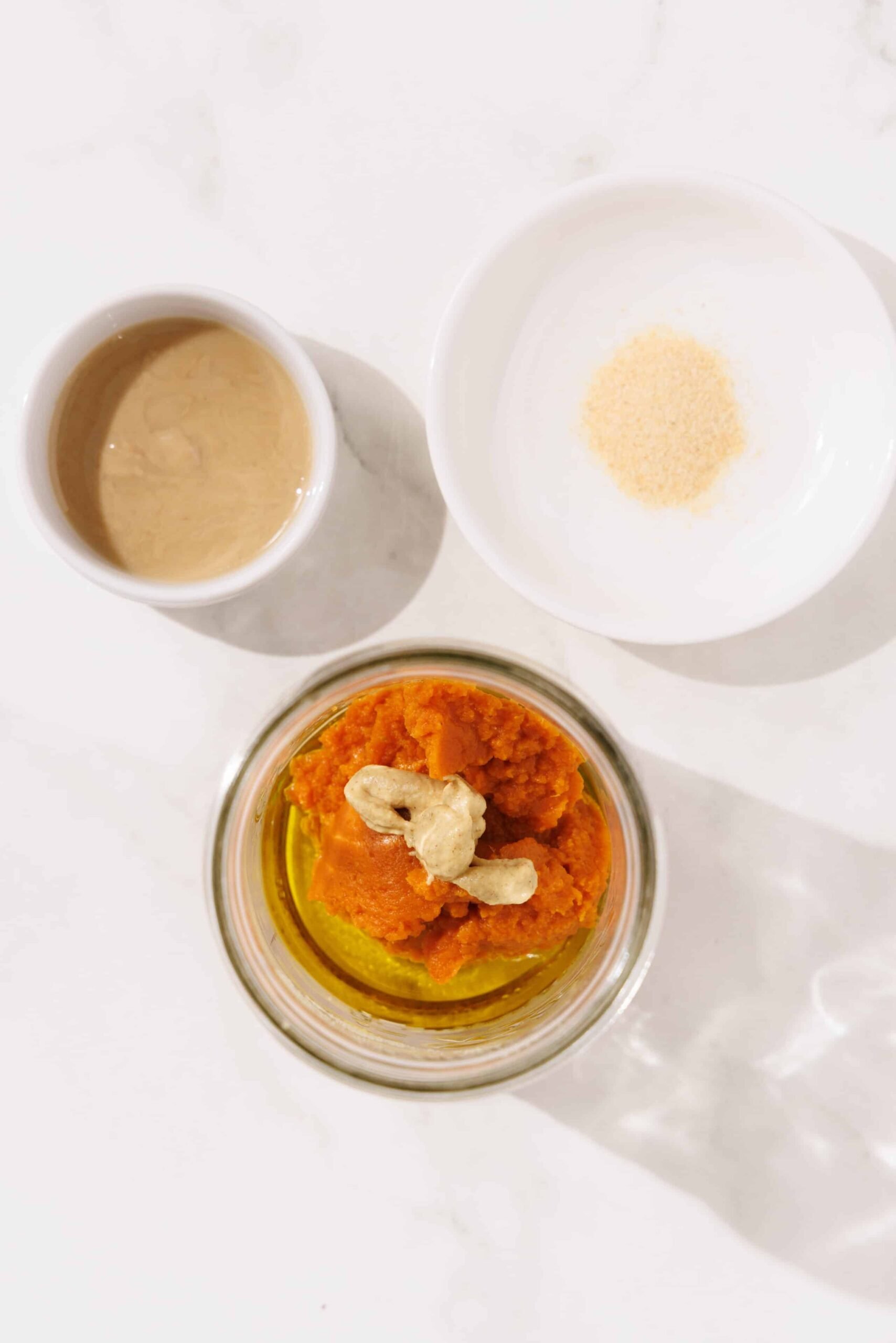Three bowls of garlic powder, tahini, and pumpkin puree.
