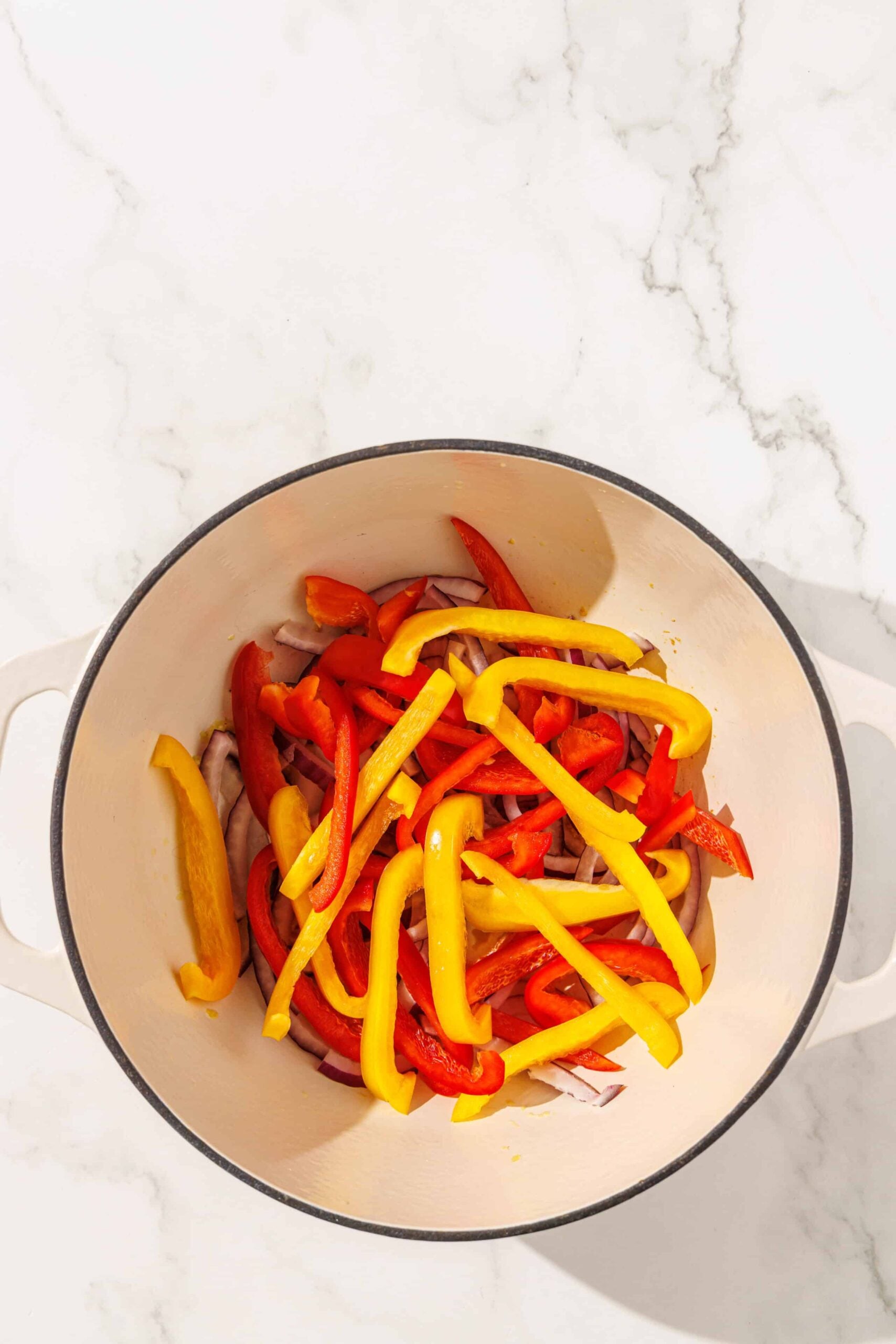 A dutch oven pot filled with sliced bell peppers.