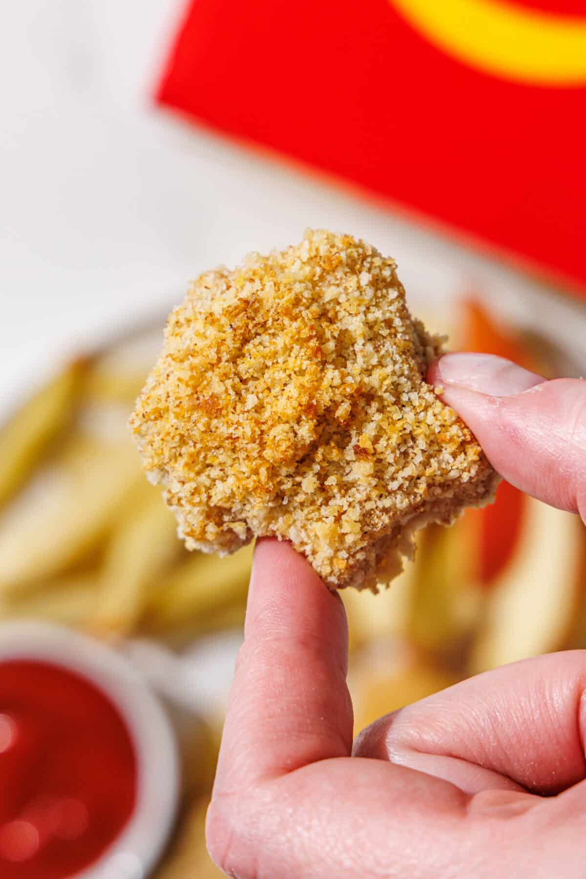 A white hand holding a tofu nugget.