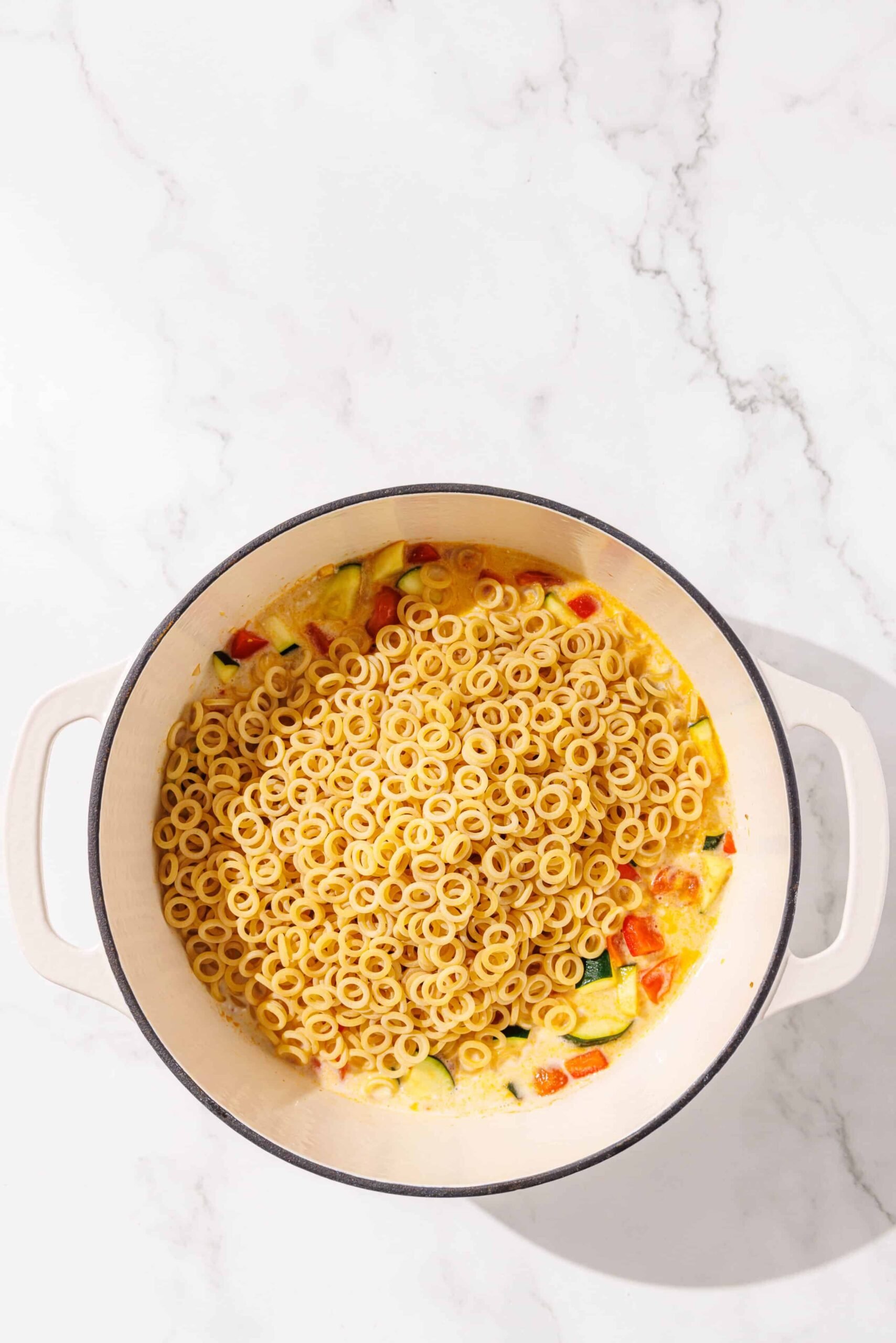 One large pot of sauteed zuchinni and bell pepper with pasta noodles on top.