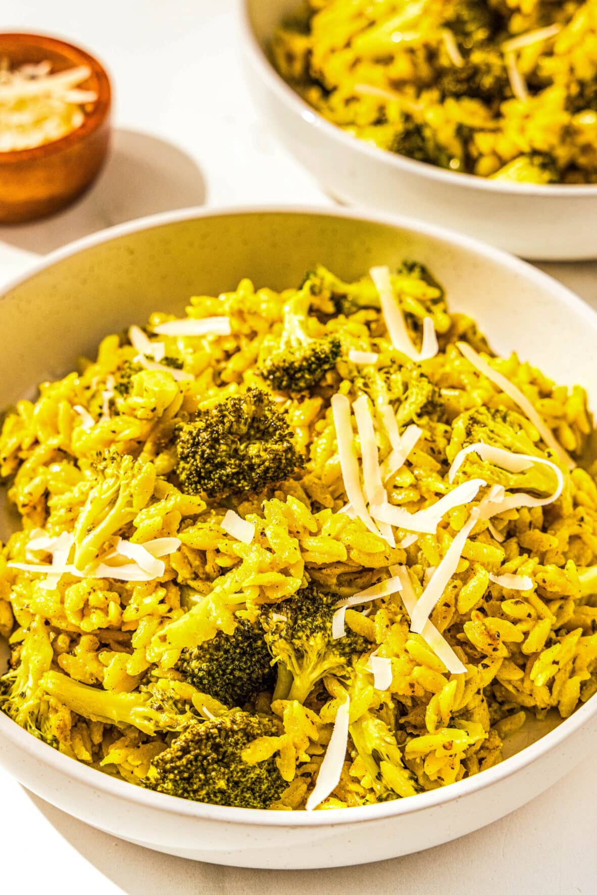 A bowl filled with orzo, broccoli, and vegan parmesan.