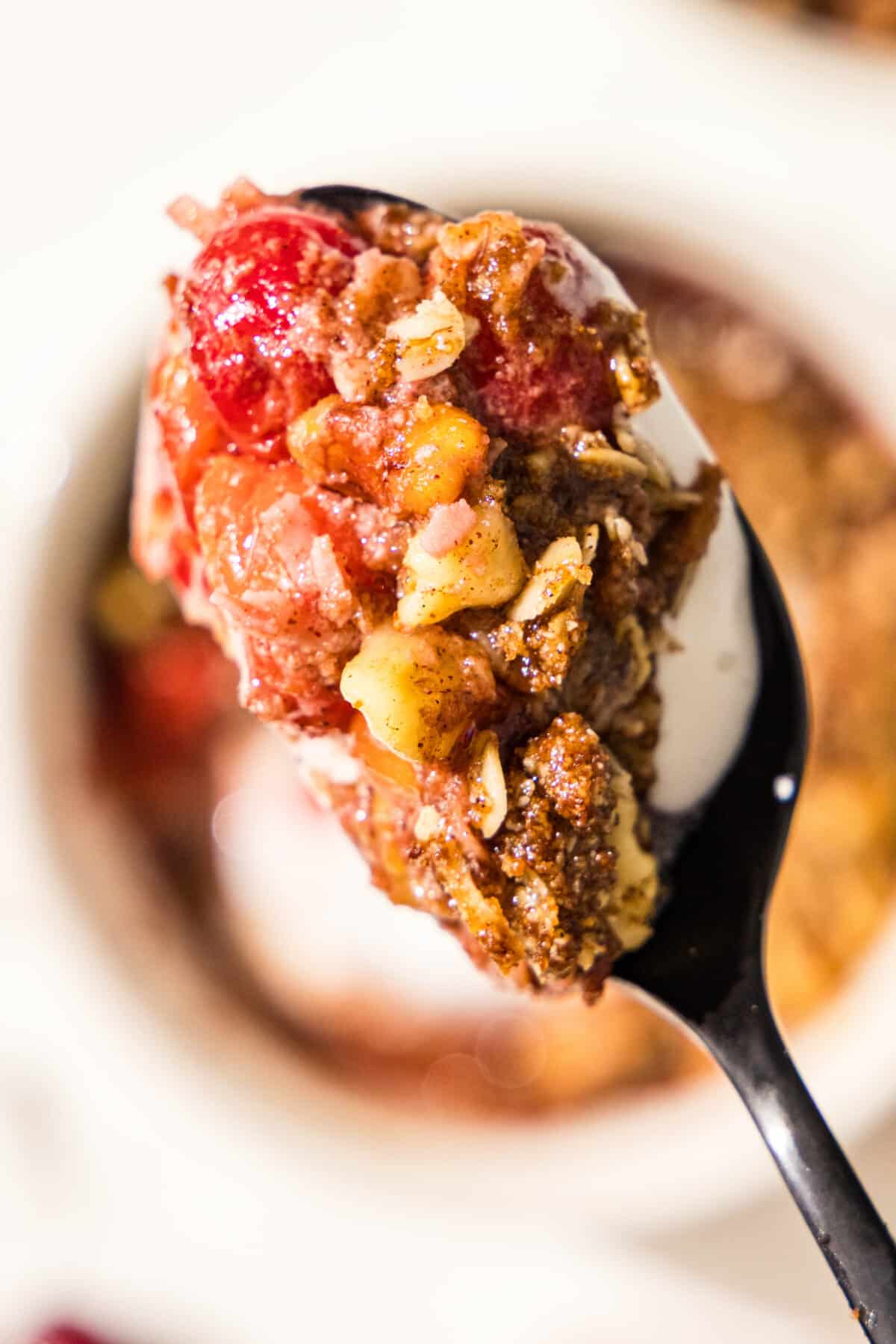 A close up bite on a spoon of a cherry crumble dessert.