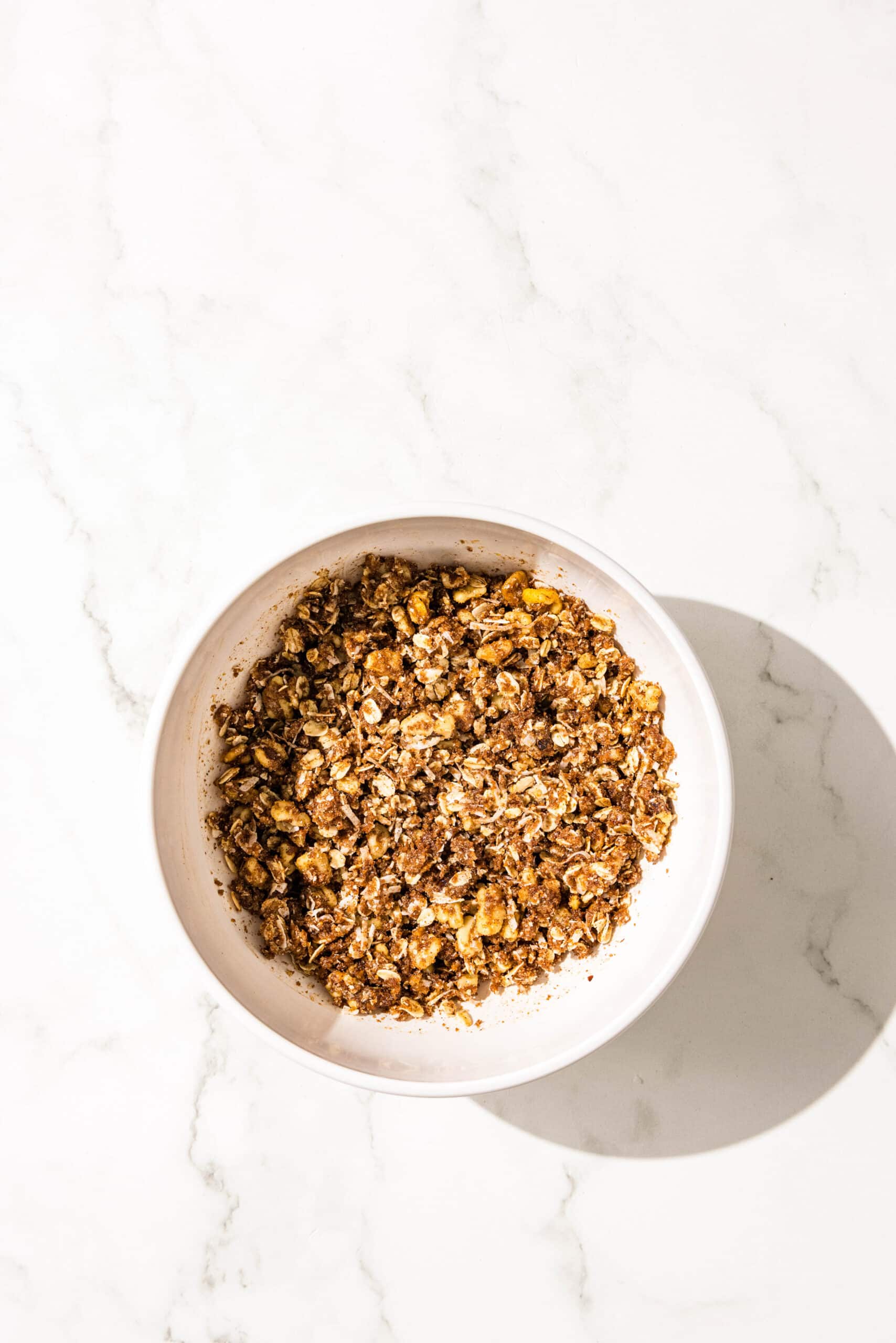 A white bowl filled with oat crumble topping.