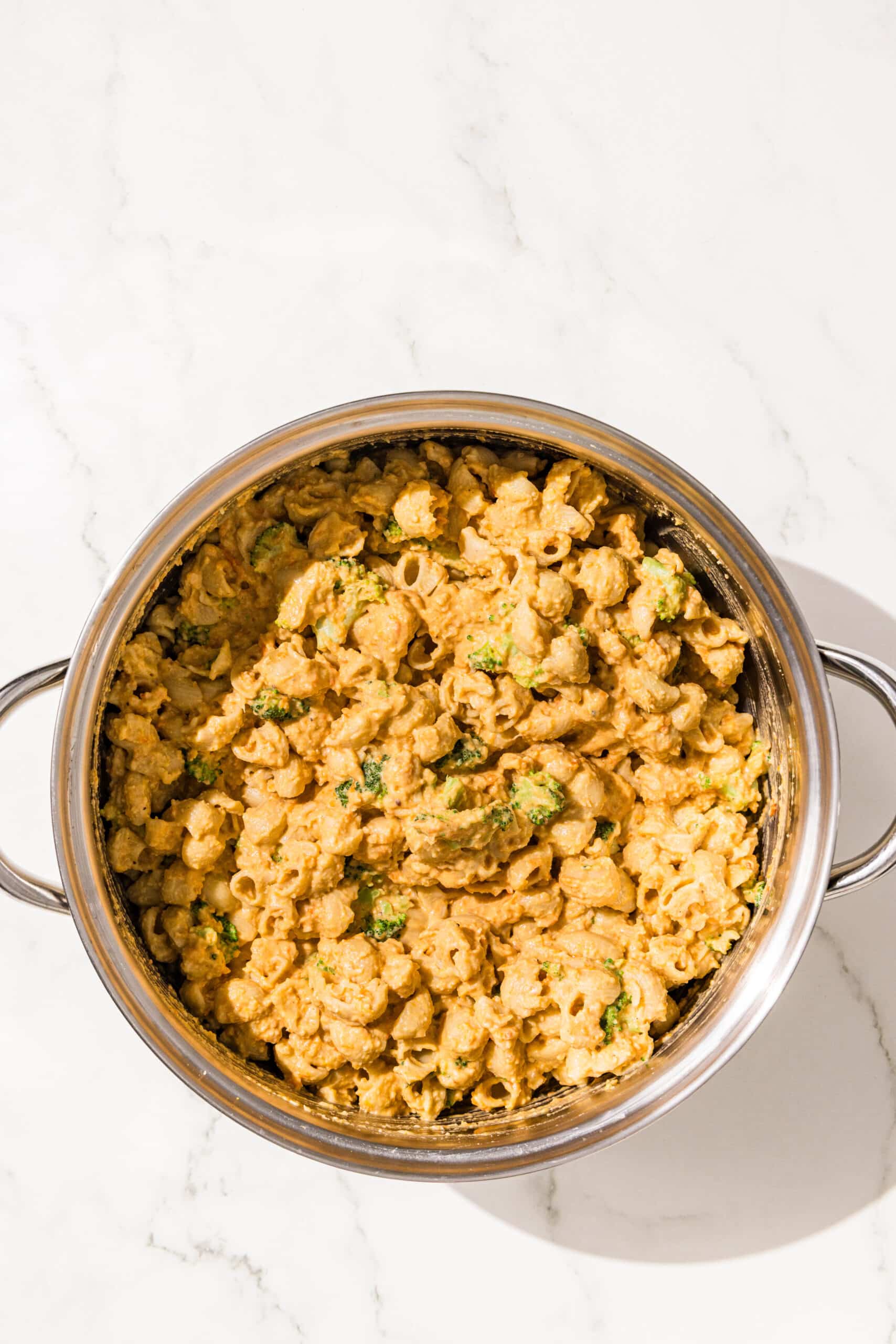 A silver pot of mac and cheese with broccoli in it.