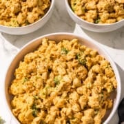 Three bowls of mac and cheese with broccoli and a black fork.
