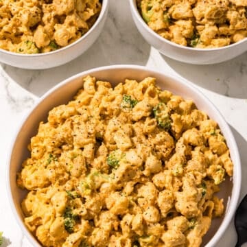 Three bowls of mac and cheese with broccoli and a black fork.