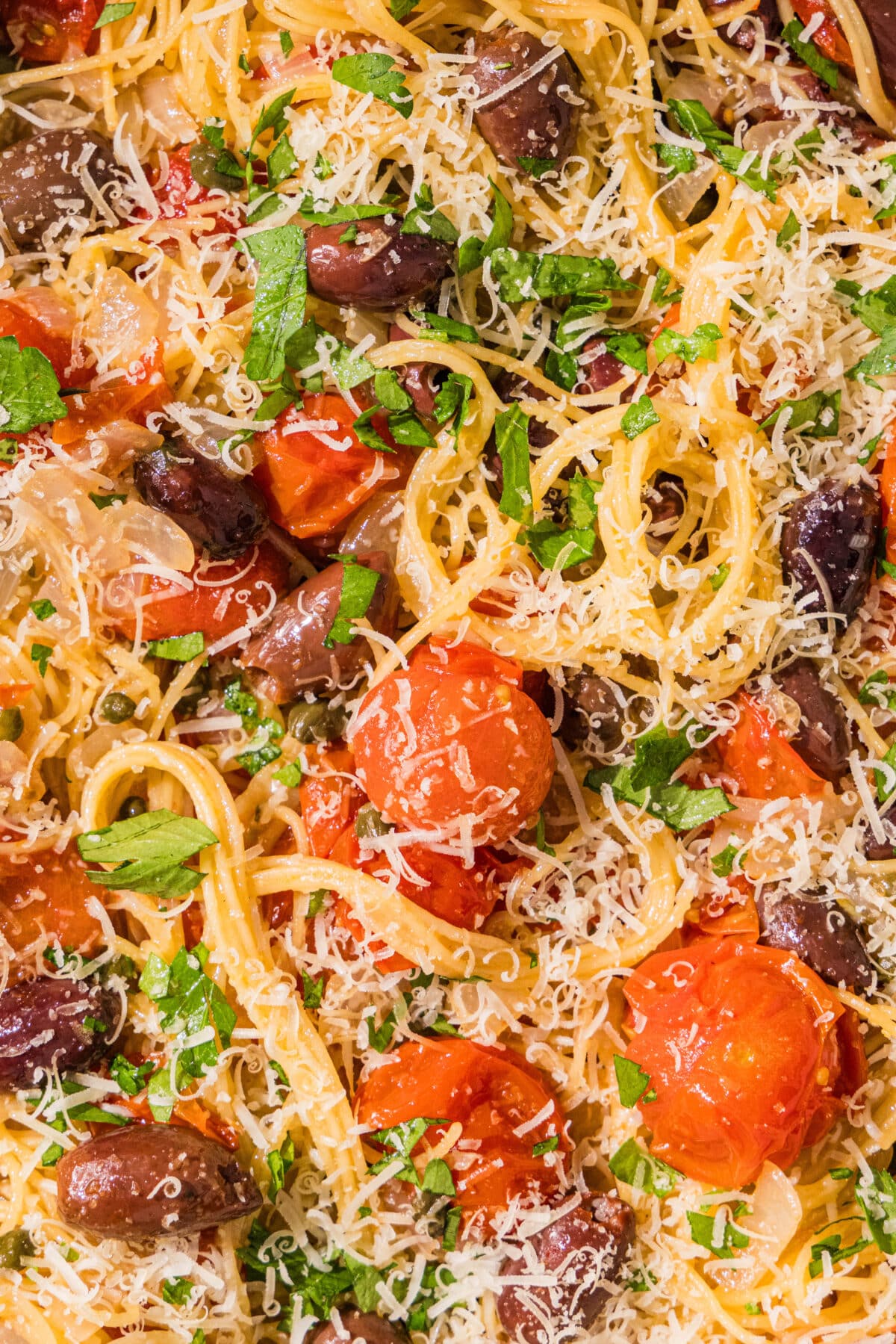 Spaghetti noodles with cherry tomatoes, kalamata olives, and capers mixed in and topped with parsley and parmesan.