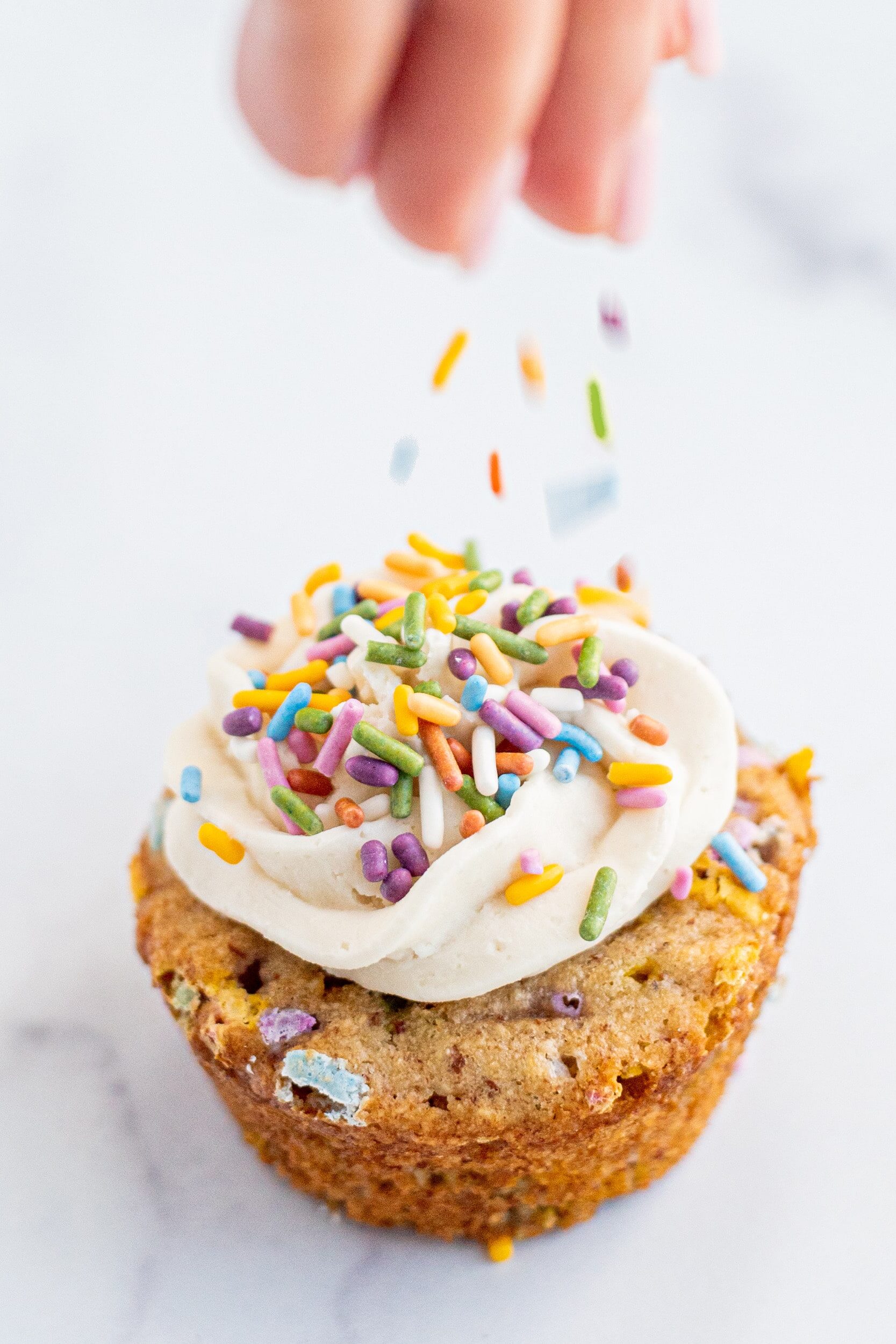 A funfetti muffin topped with frosting and sprinkles.