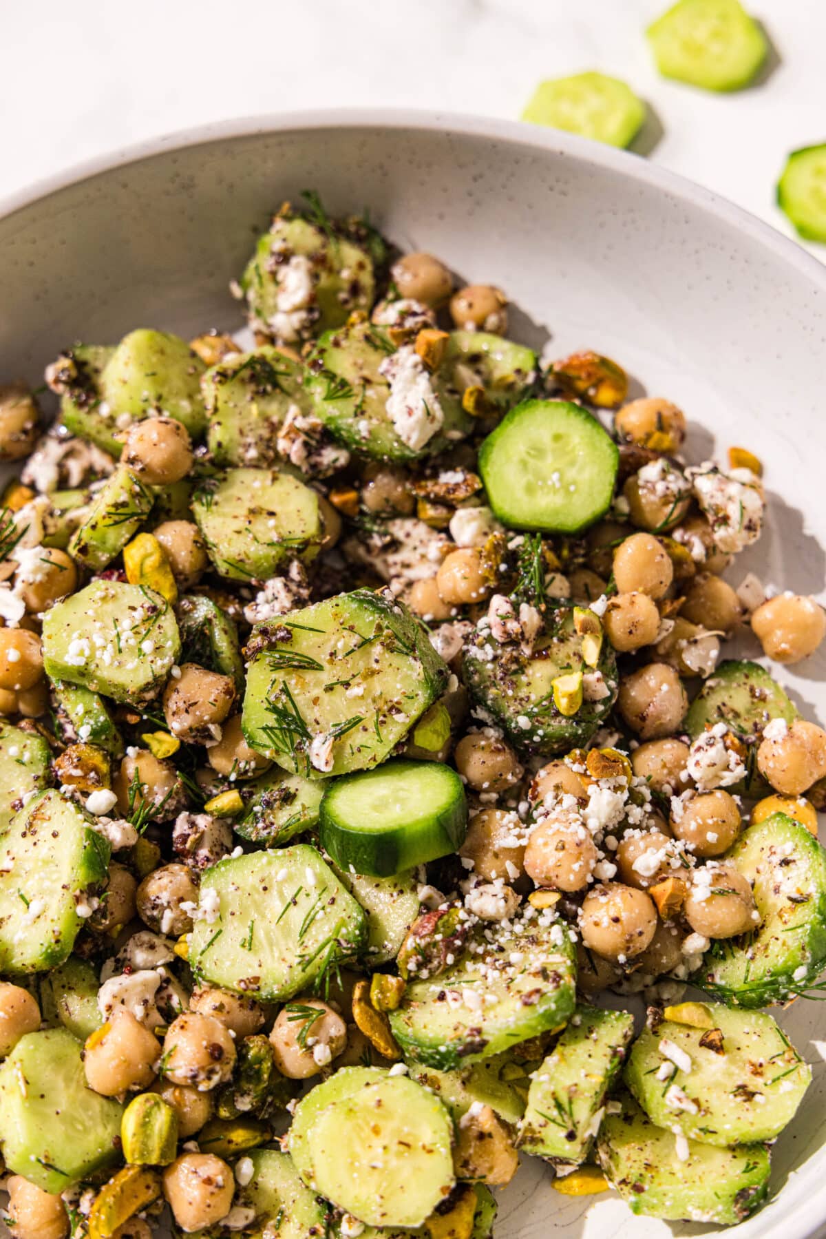 A white bowl with cucumber feta chickpea salad in it.