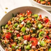 Two bowls of lentil chopped salad and a black metal fork.