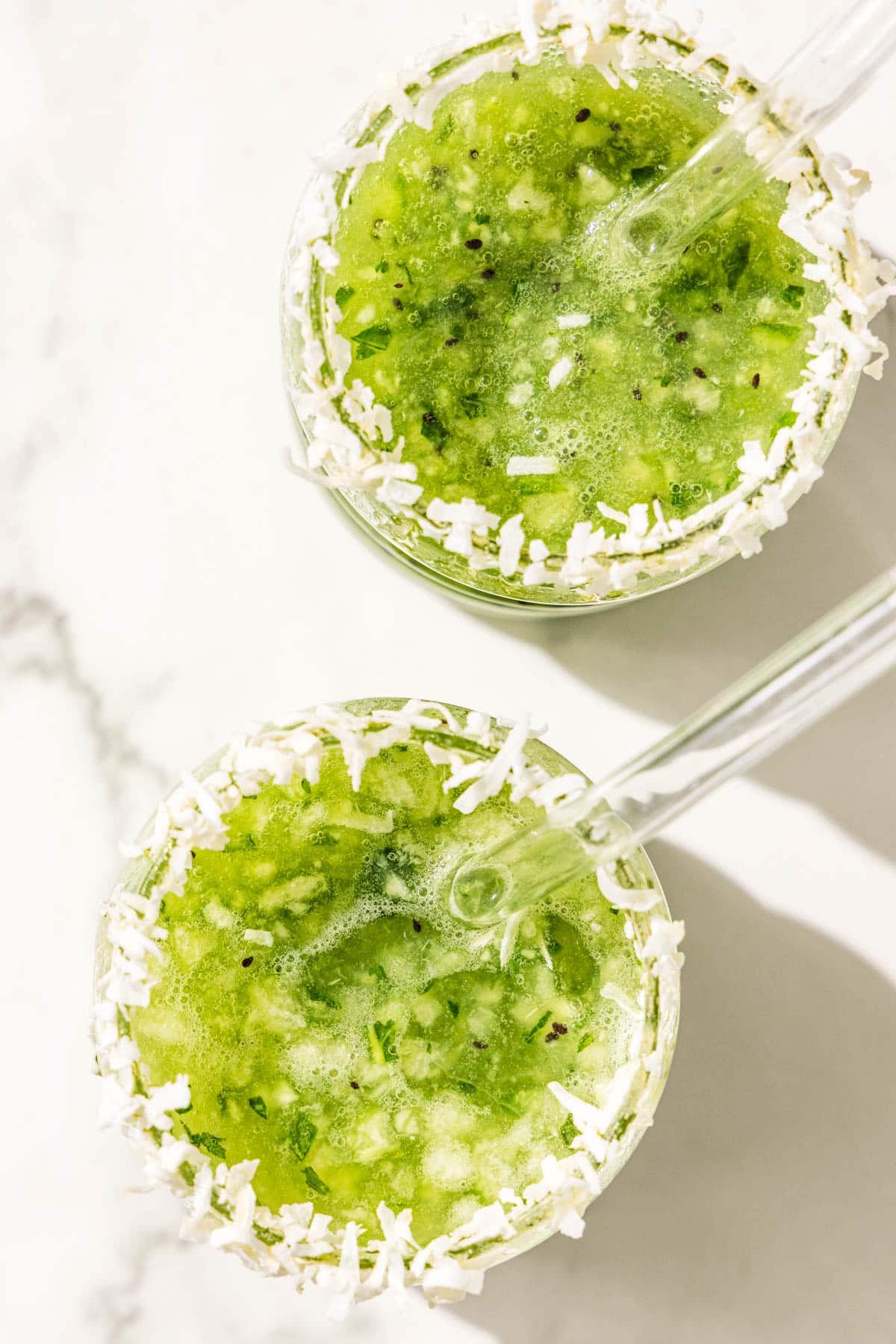 Two kiwi lime stress relief mocktails in glass jars with a shredded coconut rim.