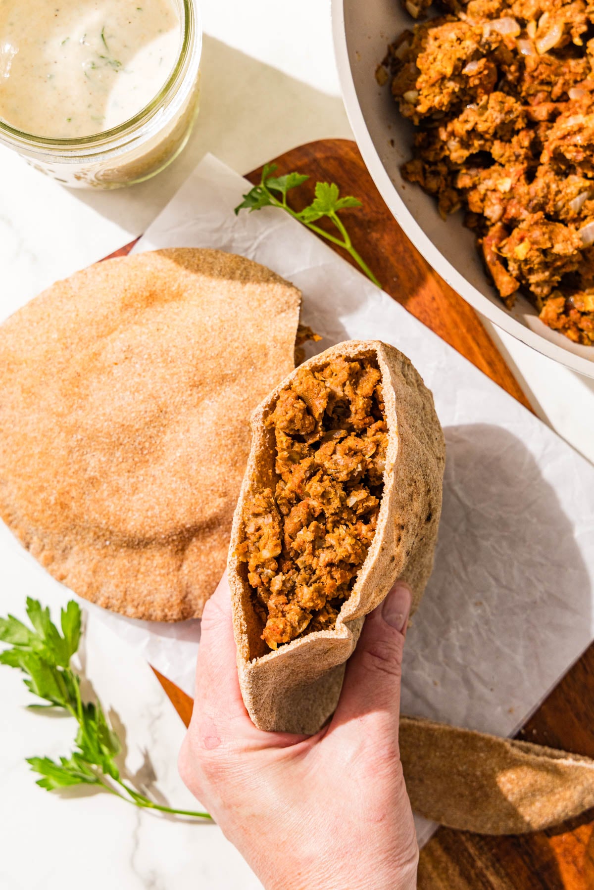 Two stuffed pitas with a meaty lentil mixture and a bowl of remaining mixture.
