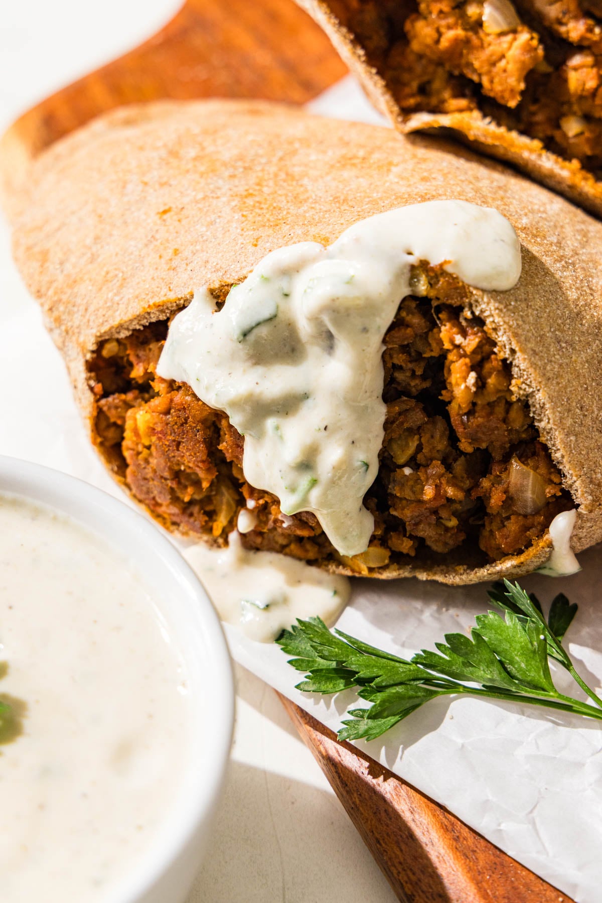 Two pitas stuffed with a lentil meaty filling. One of them has a yogurt sauce on it.