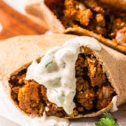 Two pitas stuffed with a lentil meaty filling. One of them has a yogurt sauce on it.