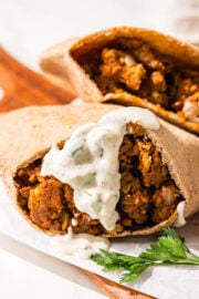 Two pitas stuffed with a lentil meaty filling. One of them has a yogurt sauce on it.