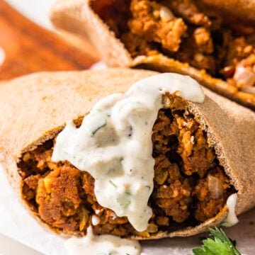 Two pitas stuffed with a lentil meaty filling. One of them has a yogurt sauce on it.