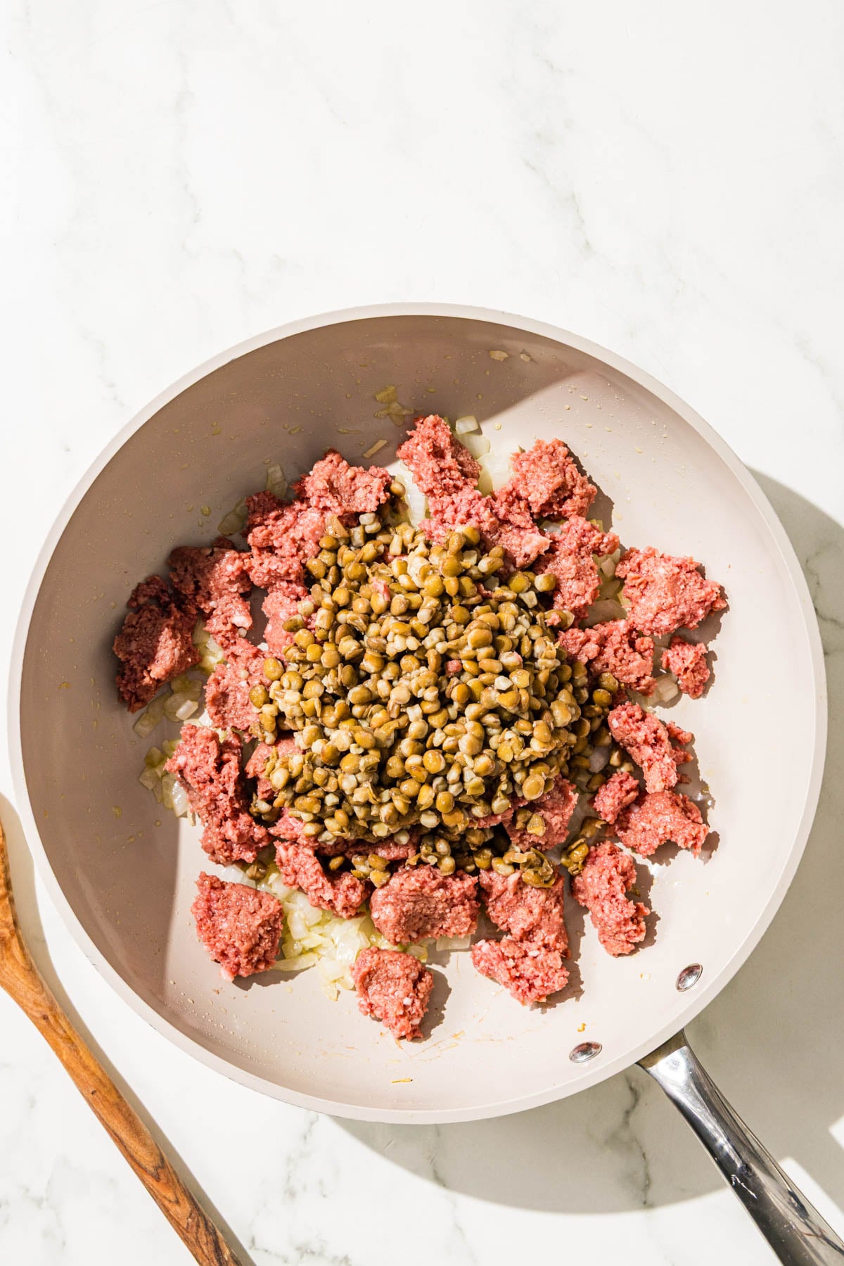 A pan with sauteed diced onion, vegan ground beef, and lentils.